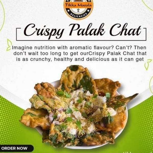 A close-up of Crispy Palak Chat, an Indian snack, topped with spices and herbs.